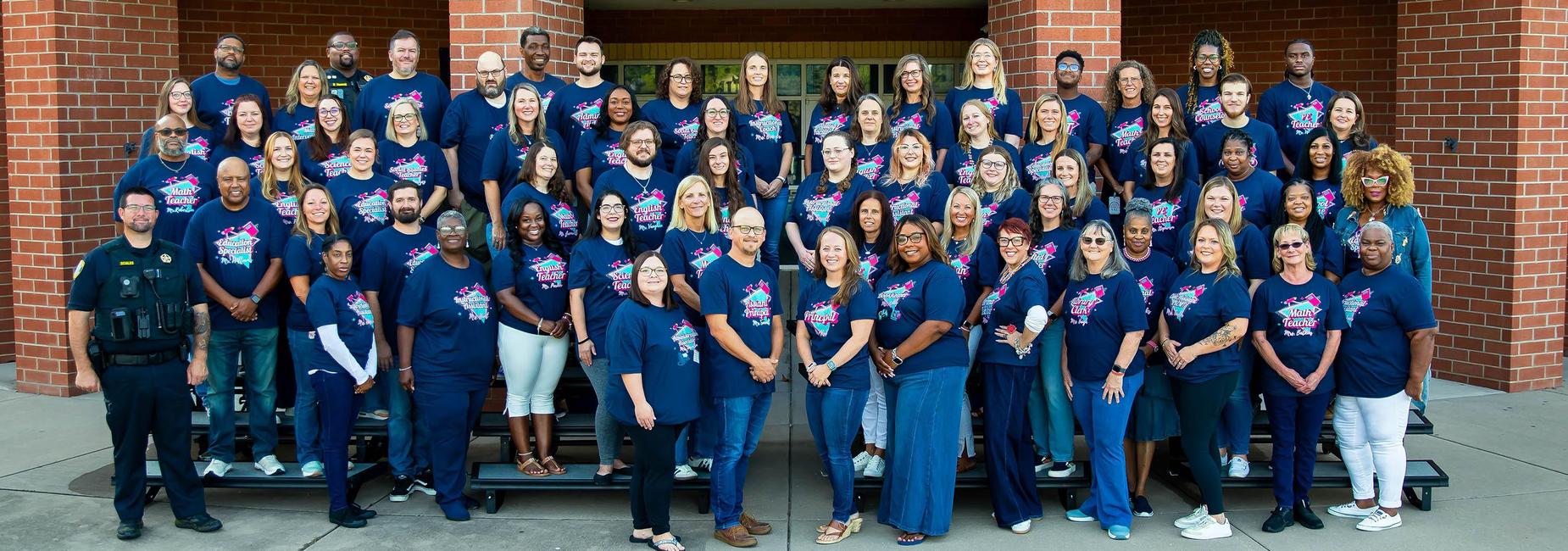 Large group of people in matching blue shirts standing on steps.