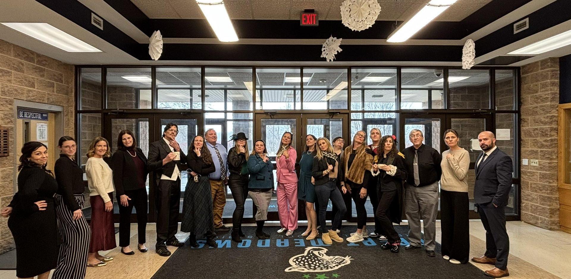 A diverse group of people posing together in a building entrance, some in formal attire.