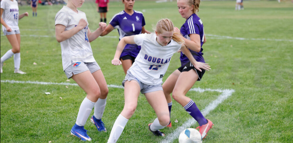 A soccer player battles for the ball surrounded by defenders.