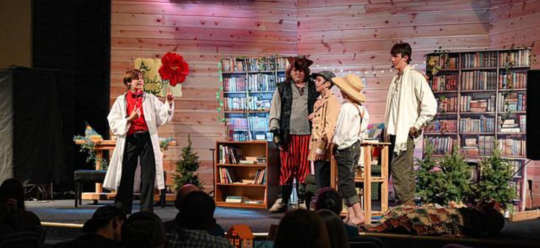 A theater performance with actors in costumes, a wooden backdrop, and a bookshelf.