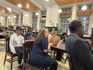 An audience of diverse individuals seated in a library, watching the panel discussion.