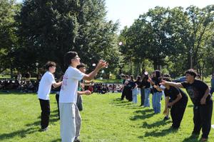 Students throw water balloons to each other in a field.