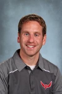 Smiling man with short brown hair in a gray polo shirt with a logo.