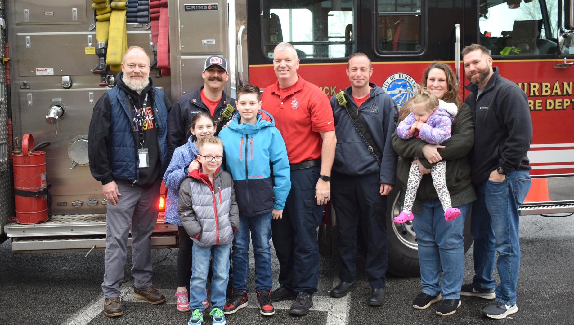 Group of people posing in front of a fire truck.