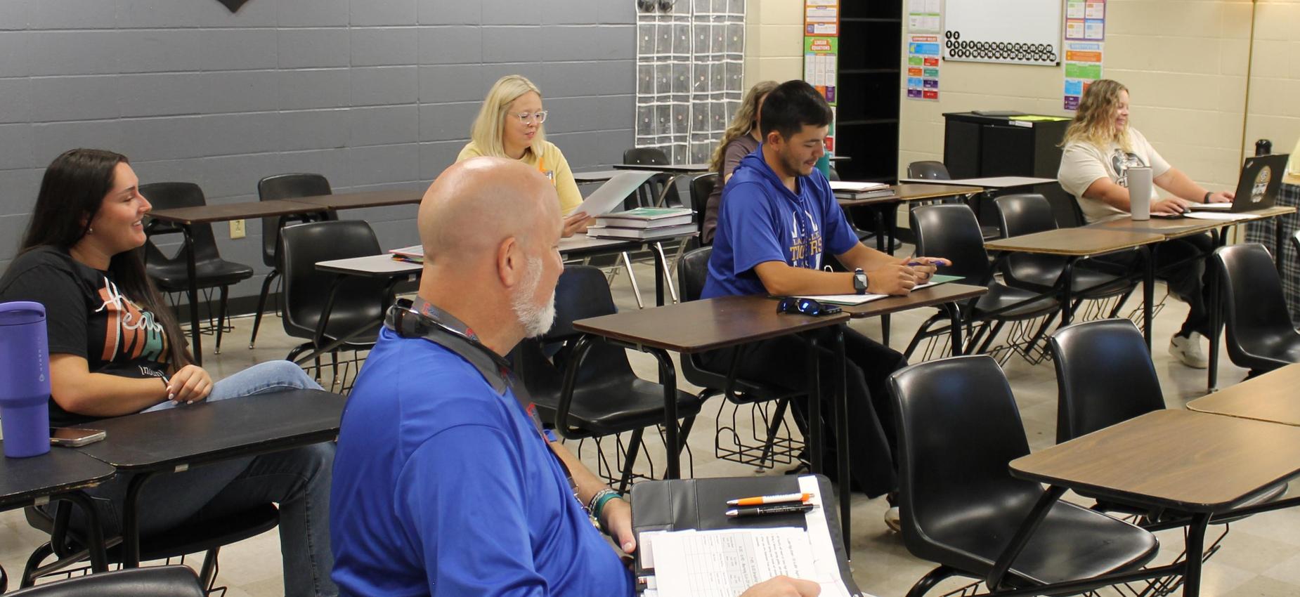 A classroom setting with several students seated at desks, engaged in a lesson.