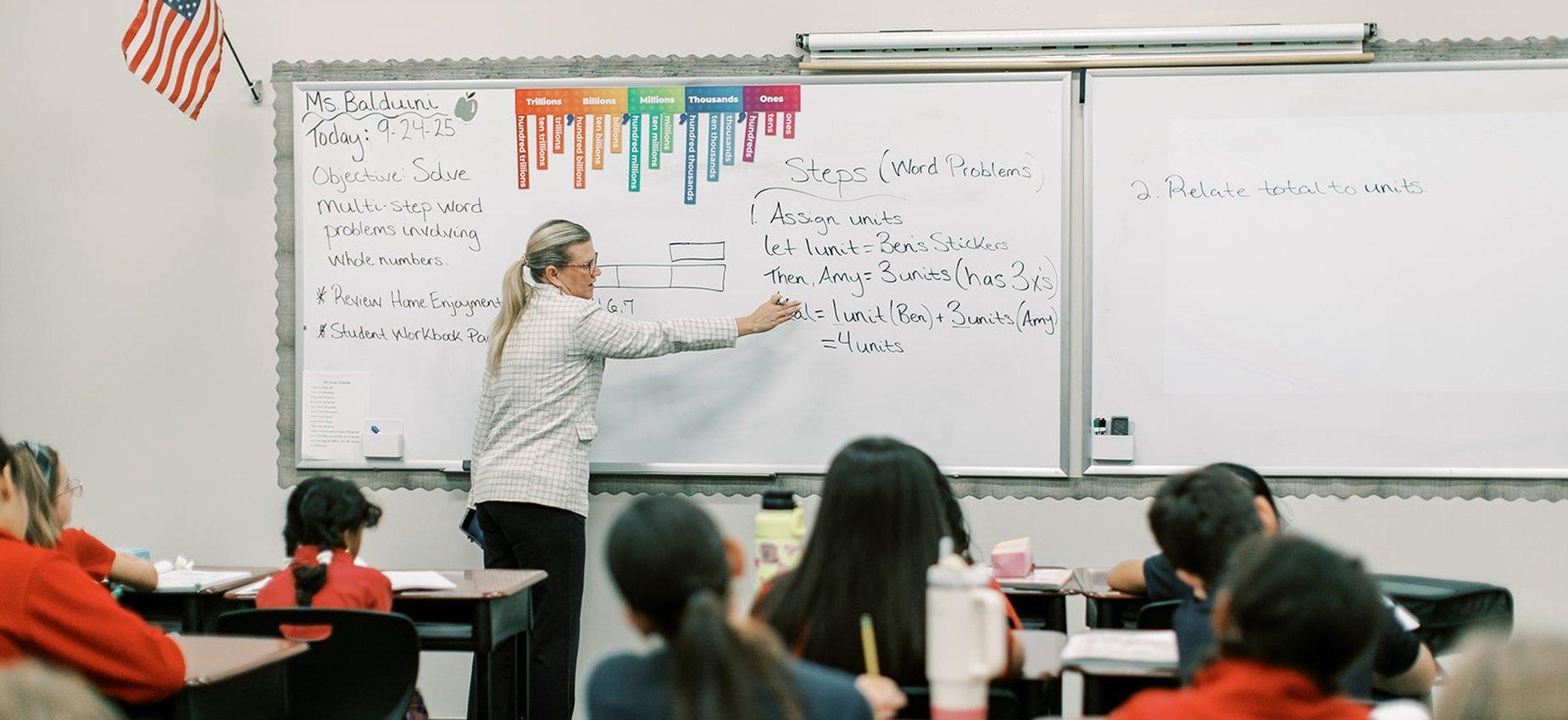 Teacher solving a word problem on the whiteboard for her class at Founders Classical Academy of Corinth