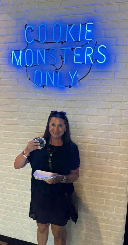 women in black dress who appears to be eating a large cookie