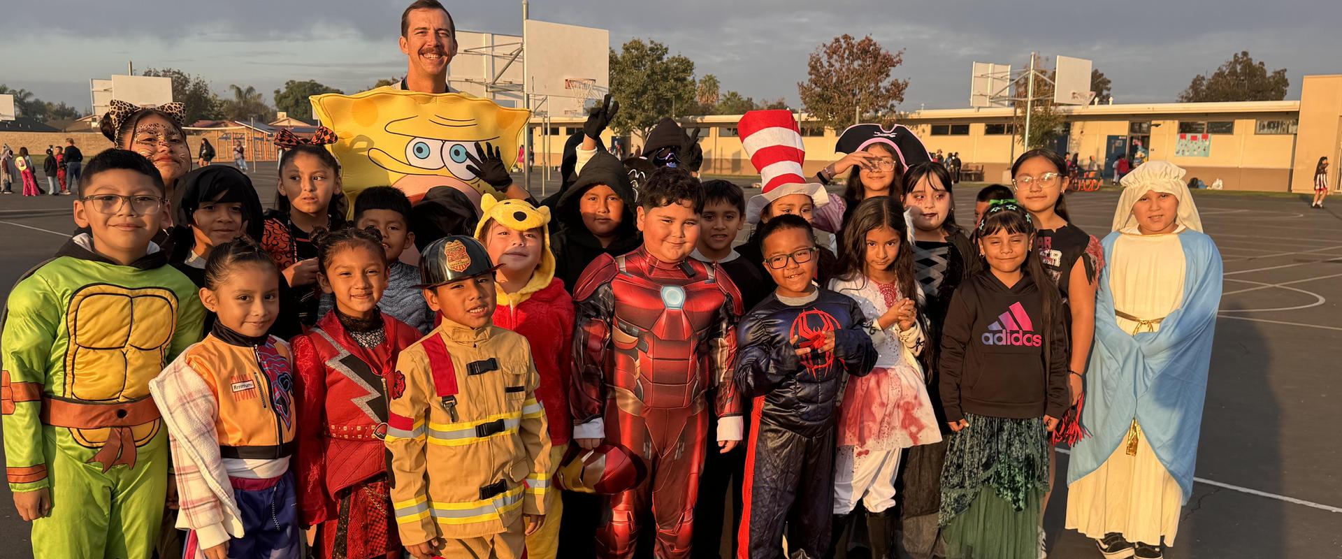 Group of children in costumes posing together on a basketball court.