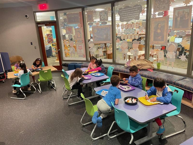 Children engaging in arts and crafts at colorful tables in a classroom setting.