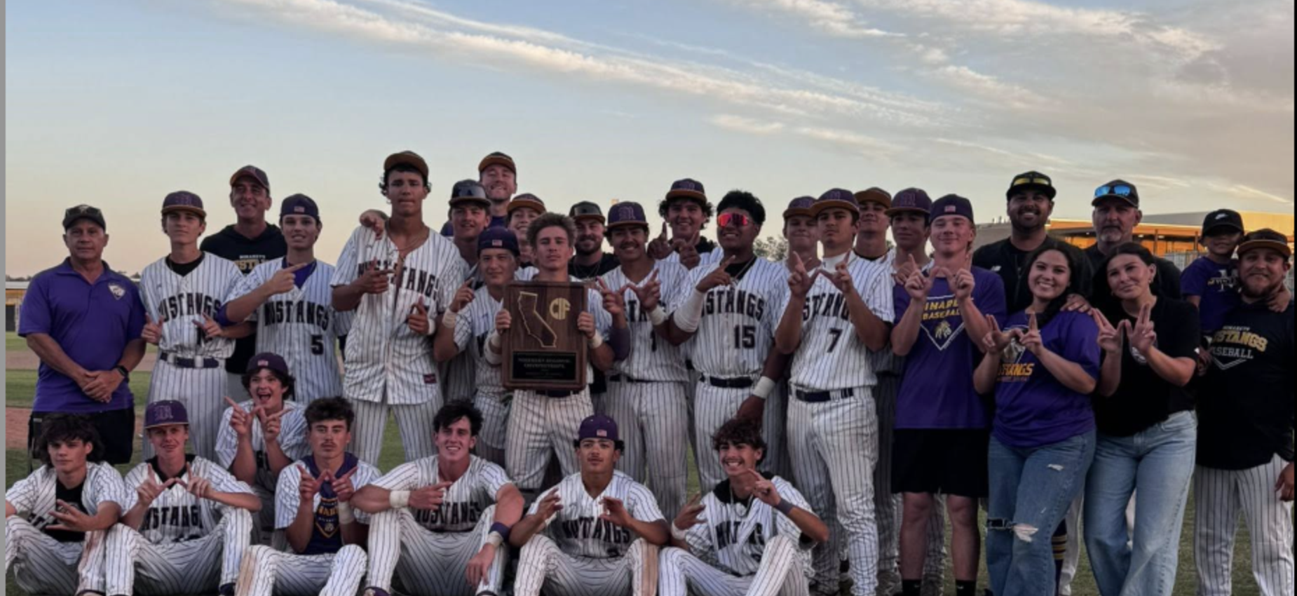 Baseball team celebrating with a trophy and medals after a victory.