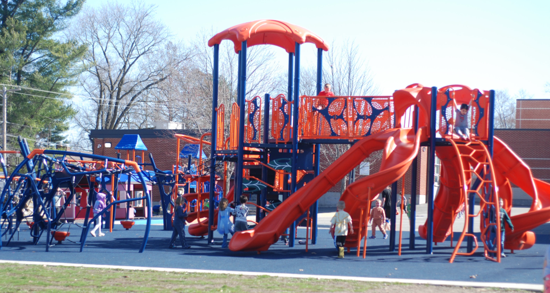 Colorful playground with slides and climbing structures filled with children.