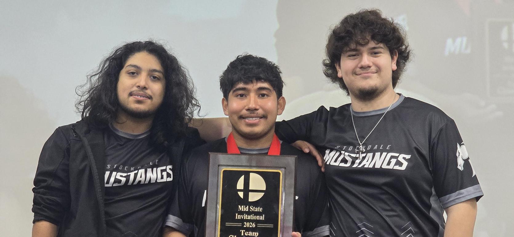 Three team members pose with a championship plaque, wearing matching jerseys.