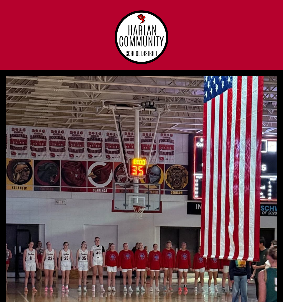 Basketball players lined up under a large American flag.