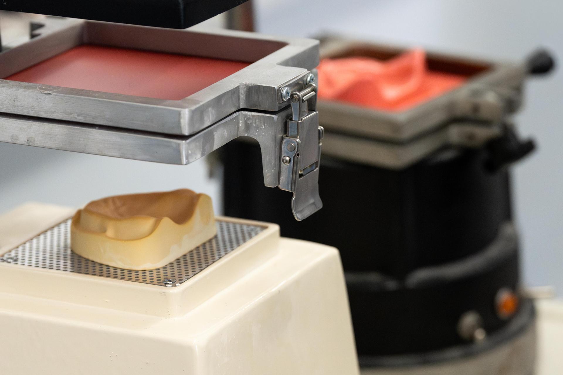 Dental mold sits under a heating press as part of the process for forming a custom dental appliance.