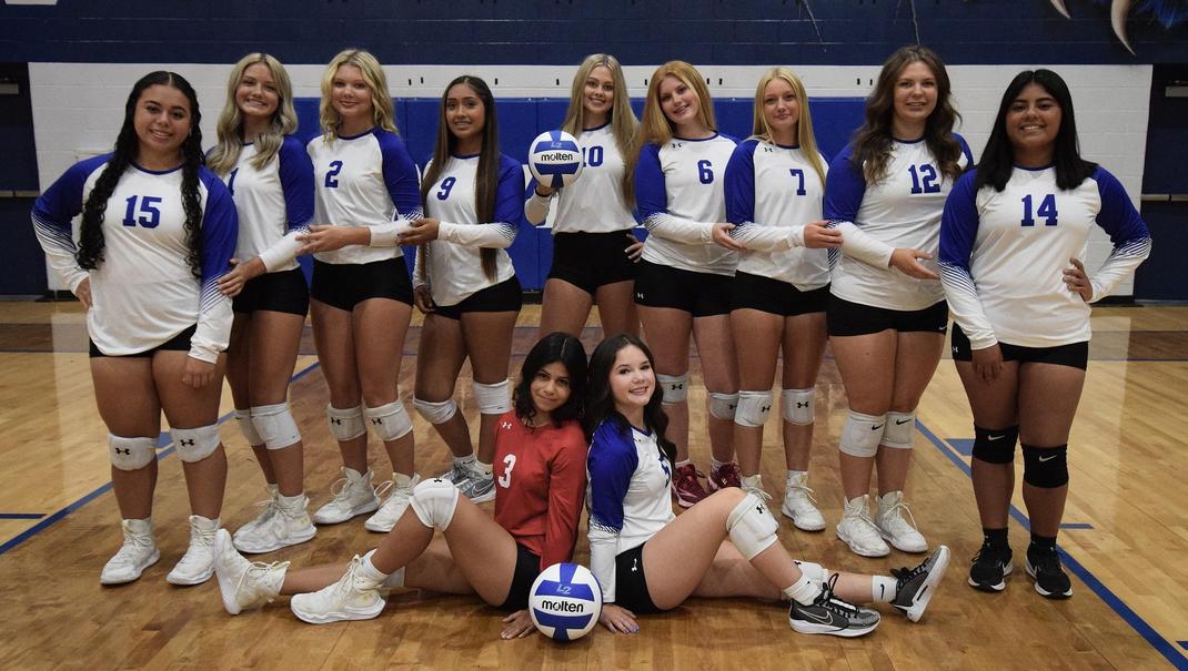 A volleyball team poses together, wearing uniforms and holding a volleyball.