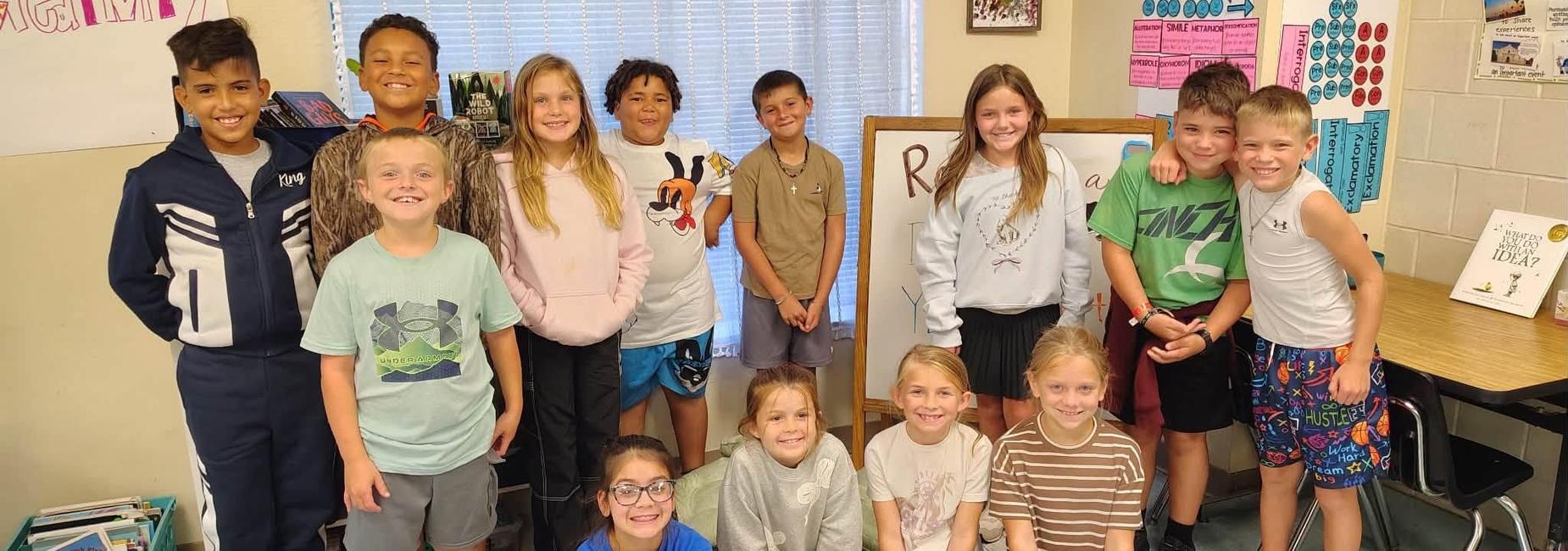 Group of children smiling together in a classroom setting.