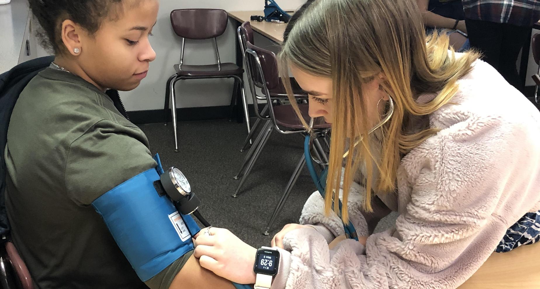 Student checking classmate's blood pressure.