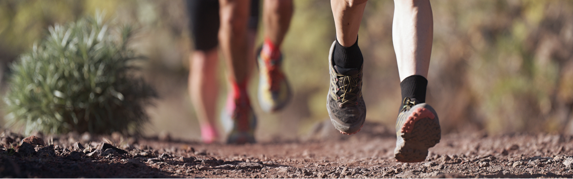 Close up of runners legs on a dry, dirt trail