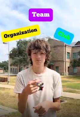 Trenton signing in HS Courtyard with text "Organization, Team, and Club" above his head