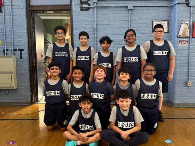 Group of children in sports uniforms posing for a team photo indoors.