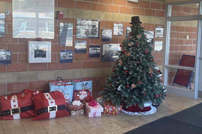 A decorated Christmas tree with gifts under it in a school lobby