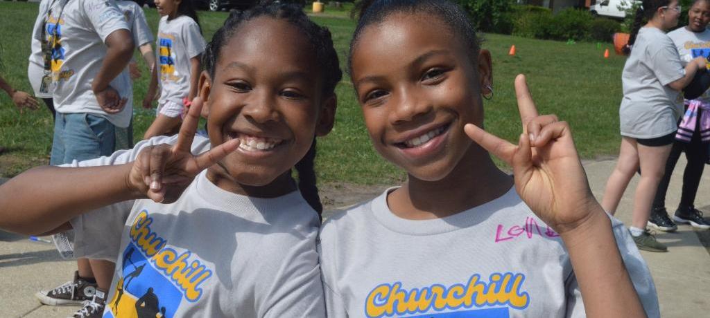 two girls with big smiles pose for camera