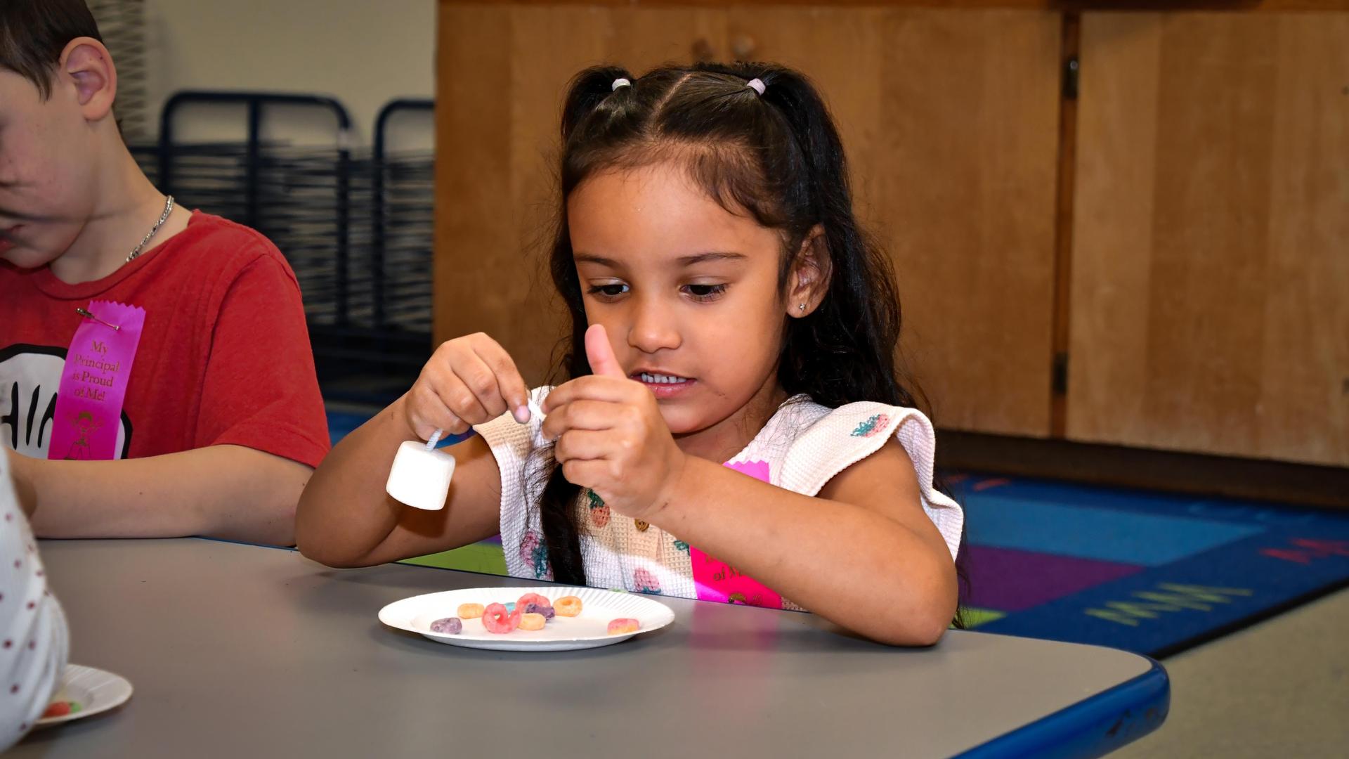 Young girl concentrating while sorting colorful candies on a plate.