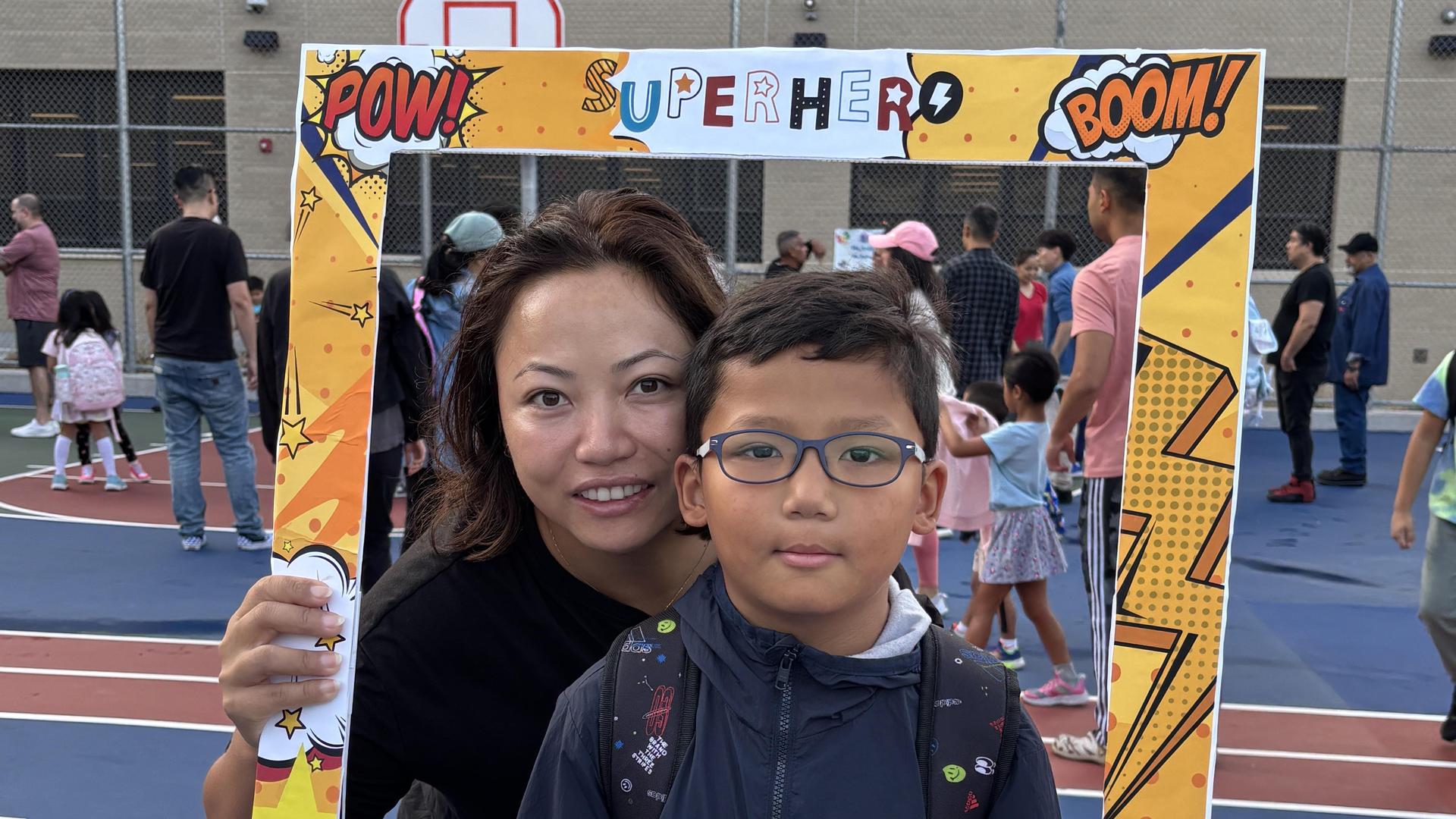 A woman and a boy in glasses smiling together through a decorative frame.