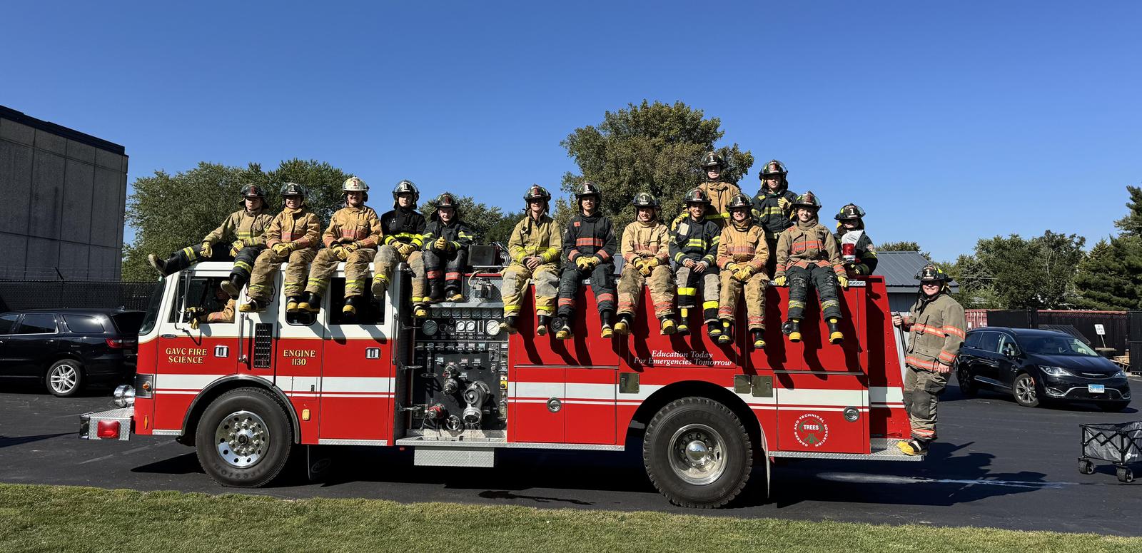 Fire Science students sit on red fire truck.