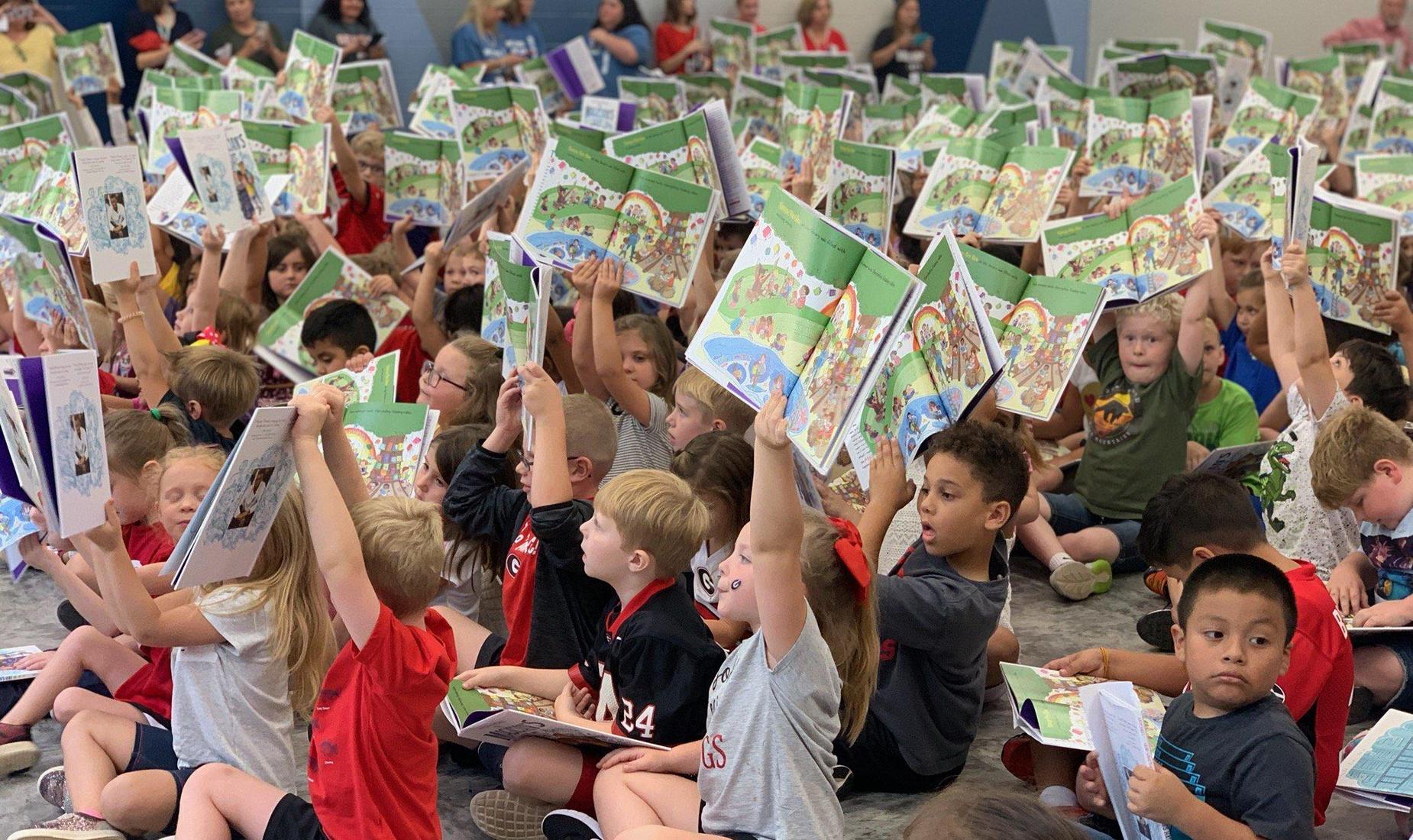 Students sitting holding up books