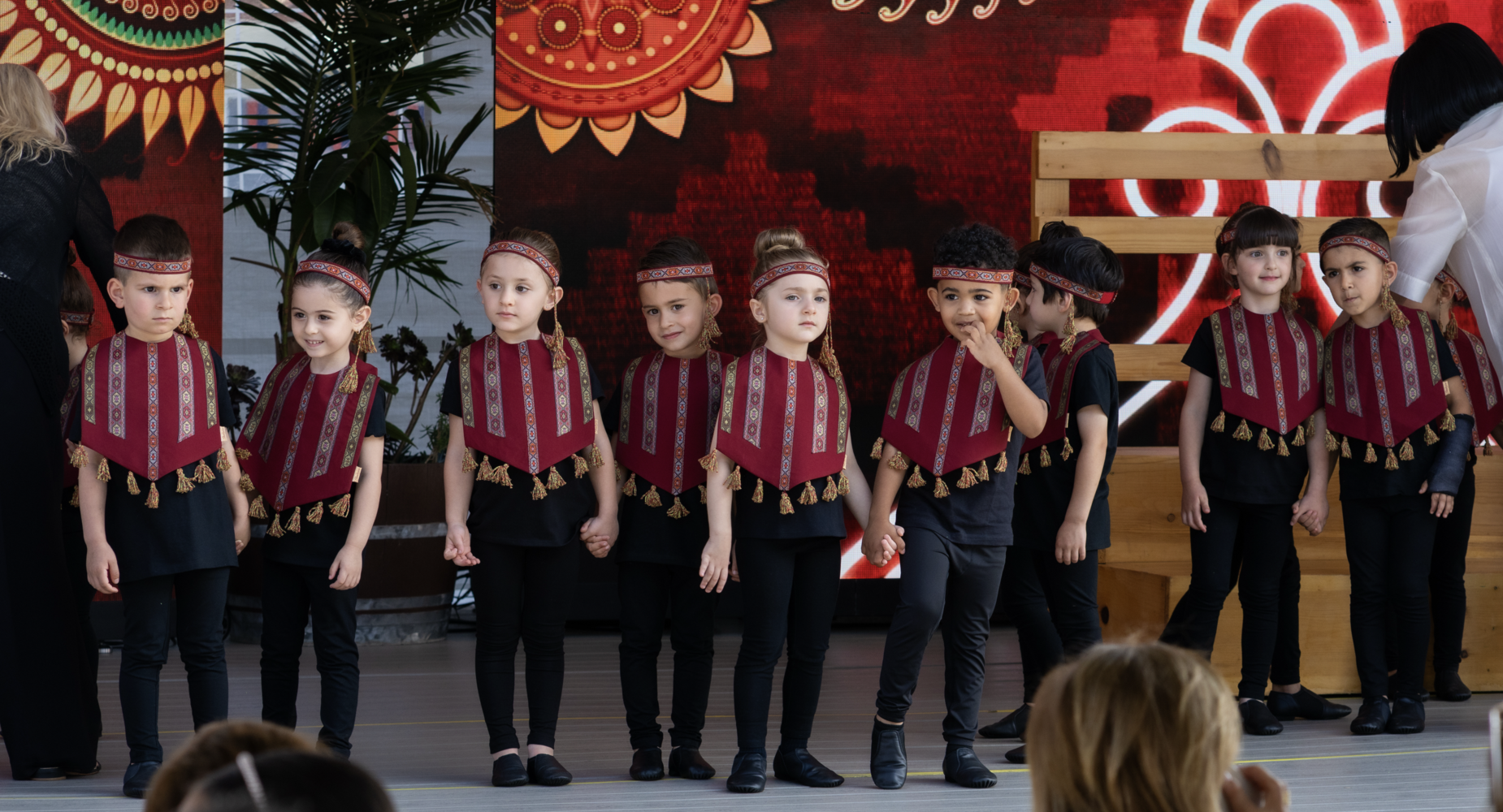 Children dressed in traditional costumes stand together on stage.