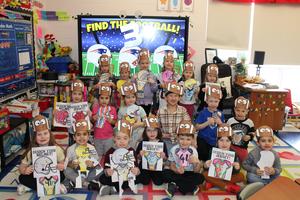 class of kindergarteners with football crowns holding colored jerseys and helmets