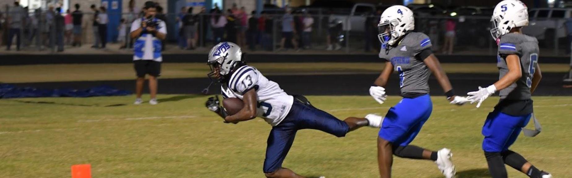 Football player in action diving for a touchdown, with defenders trailing behind.