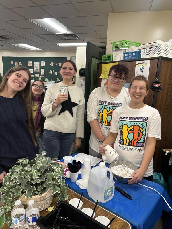 Students smiling and preparing food together in a classroom setting.