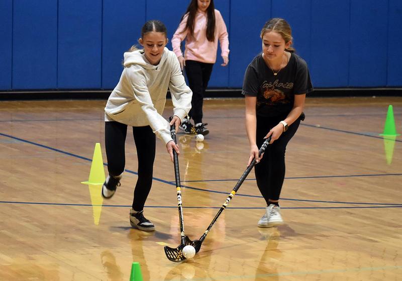 Two students with hockey sticks running