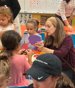 A kindergarten student and her mother cutting out a circle for her sukkah decoration