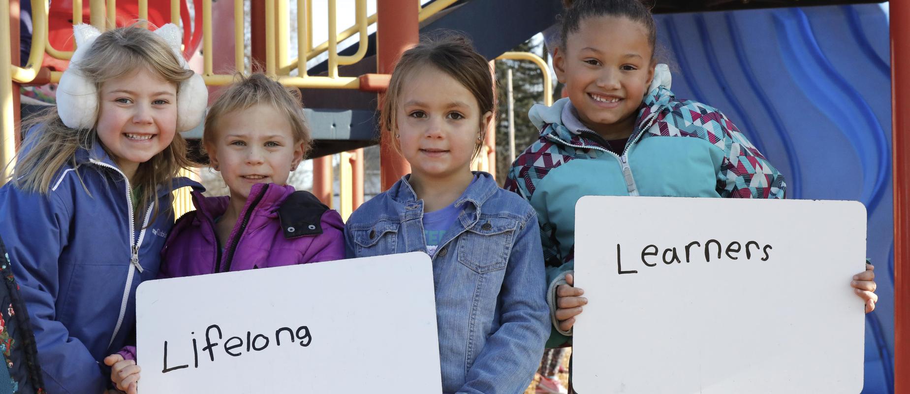 4 girls holding sign that says lifelong learners outside