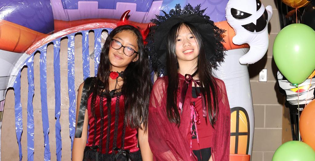 One girl dressed as a devil, the other girl dressed as a witch.
