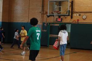 Children gathered near a basketball hoop, preparing to play.