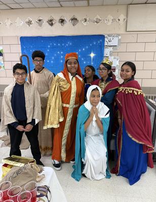 Group of children dressed in costumes, posing in front of a blue starry backdrop.
