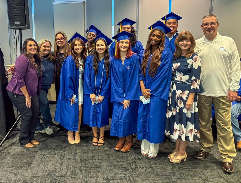 A group of students in graduation caps and gowns with teachers