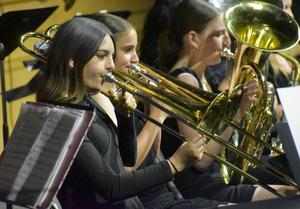 Trombone players in formal attire performing together.