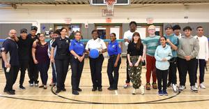 a group of officers, students and staff pose in front of a Goalball net