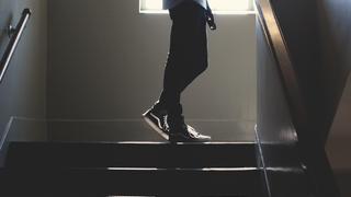 Person walking up dark stairs with natural light from a window
