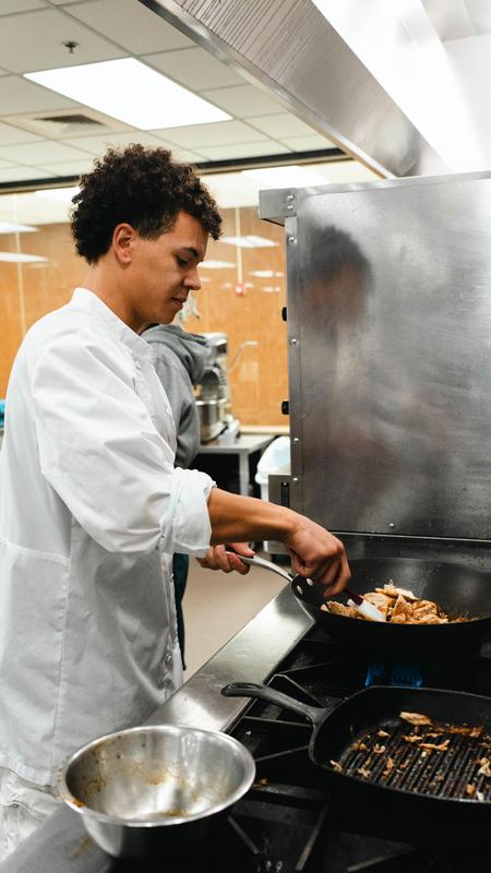 FHS culinary student cooking food on the stove in lab kitchen.