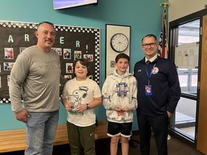two middle school students standing between two men