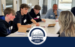 Students and teachers engage in discussion around a table.