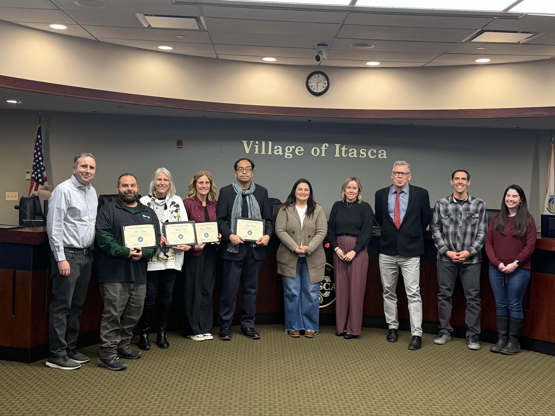 group of board members and teachers smiling at a board meeting holding their award