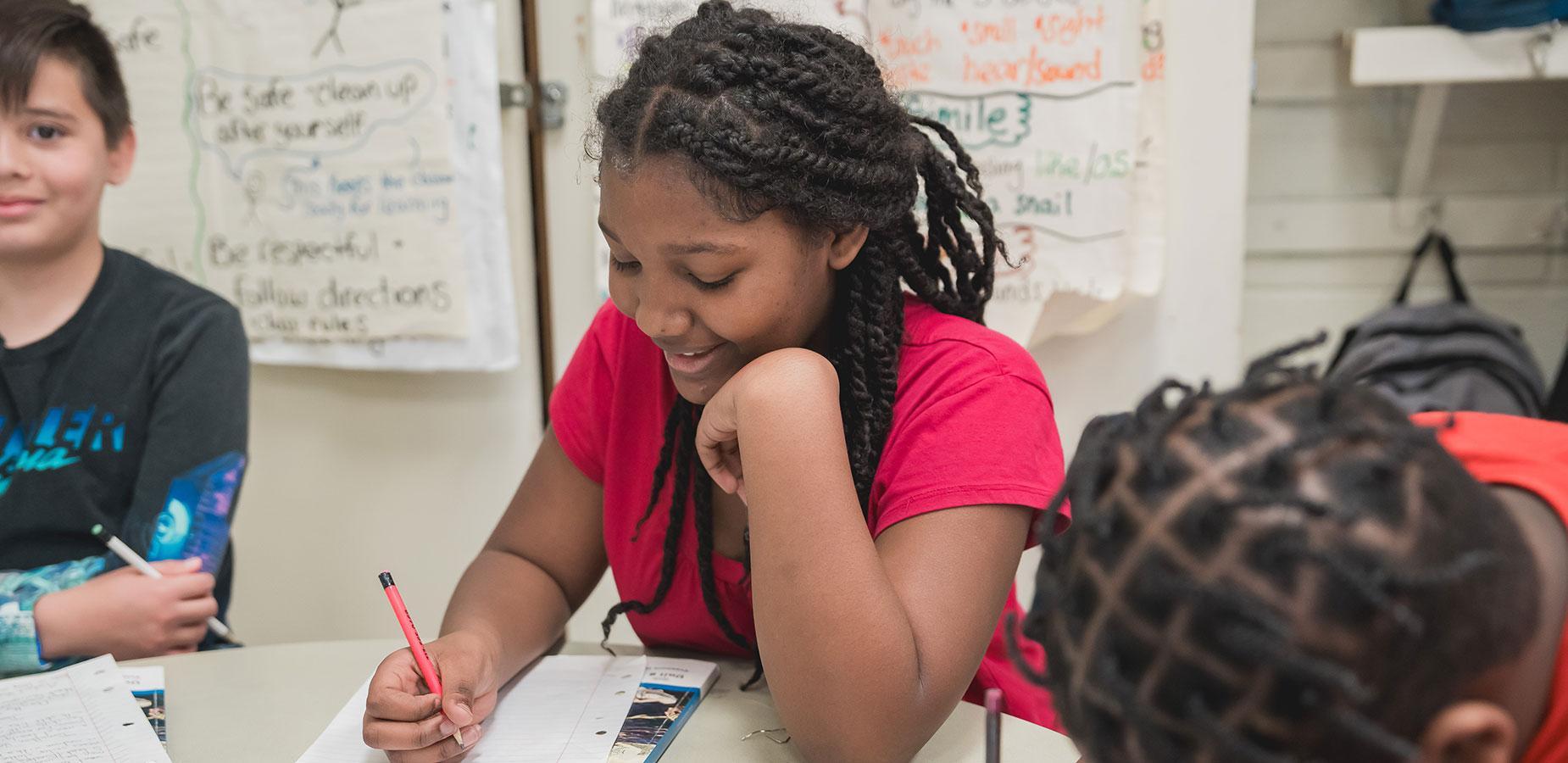 middle school student writing in notebook