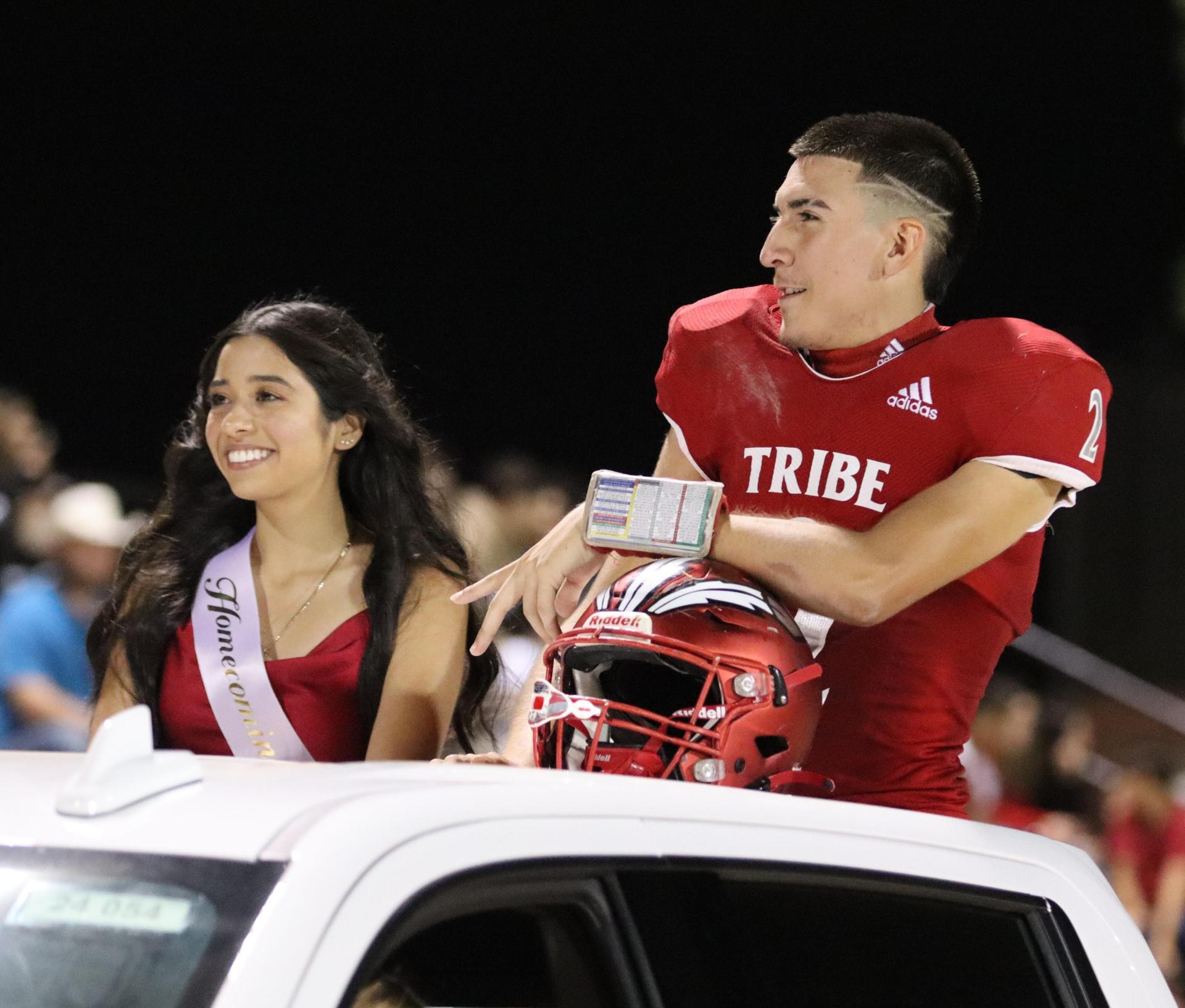 homecoming king and queen candidates entering the stadium in trucks